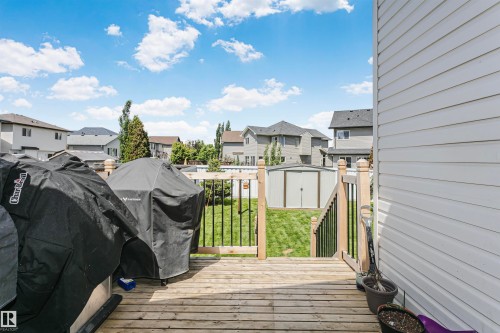 Wooden deck with a light wood railing and black vertical balusters, leading down to a green lawn - 4228 162 Avenue, Edmonton, AB 