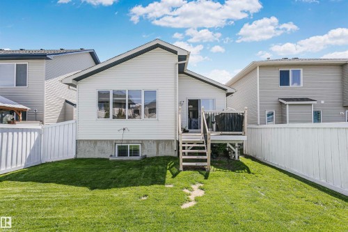 Expansive backyard featuring a manicured lawn, white privacy fencing, and an elevated wood deck with stairs - 4228 162 Avenue, Edmonton, AB 