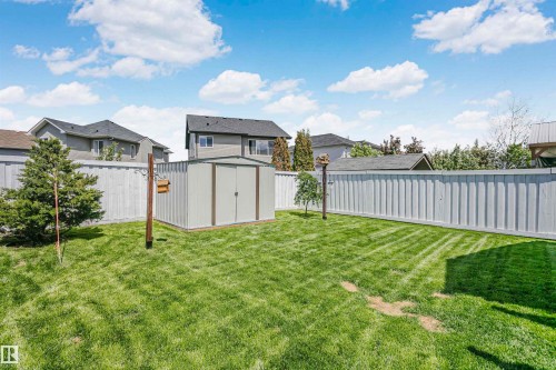 Expansive backyard featuring a metal storage shed, a manicured lawn, and a tall privacy fence - 4228 162 Avenue, Edmonton, AB 