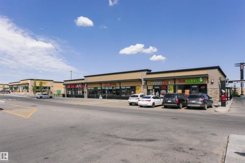 Retail strip center featuring multiple storefronts with large display windows, a neutral-toned facade, black soffits, and ample paved parking - 4228 162 Avenue, Edmonton, AB 