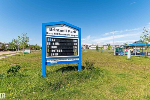Community park sign with a blue frame, a large message board, a paved pathway, and a covered picnic area - 4228 162 Avenue, Edmonton, AB 