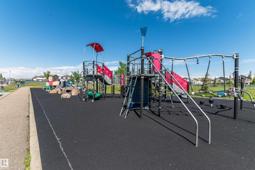 Contemporary outdoor playground structure featuring multiple slides, climbing elements, and a soft rubberized surface - 4228 162 Avenue, Edmonton, AB 