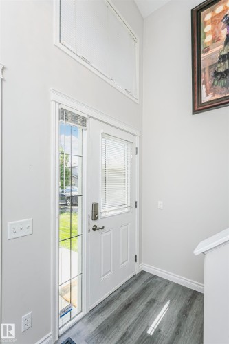 Entryway featuring a white paneled door with integrated blinds, a full-length sidelight with divided lites, and a transom window above - 4228 162 Avenue, Edmonton, AB 