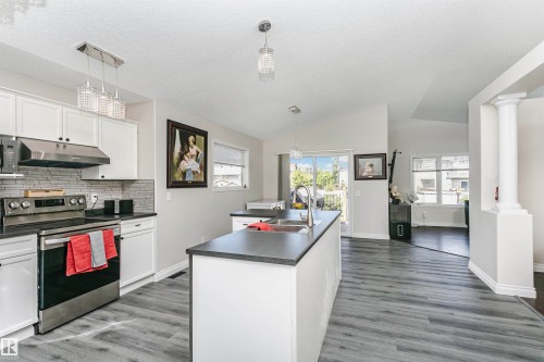 Kitchen featuring white cabinetry, stainless steel appliances, dark countertops, and a subway tile backsplash - 4228 162 Avenue, Edmonton, AB 