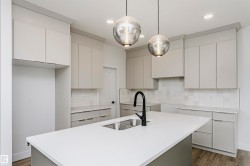 Kitchen featuring a large central island with an undermount double sink and matte black gooseneck faucet - 
