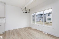 Bright interior space featuring a multi-pane window, wood-finish flooring, and a contemporary black chandelier - 