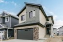 Contemporary multi-story residence featuring light beige and gray siding, a dark gray garage door, and stone facade accents - 6210 Dansereau Crescent, Beaumont, AB 