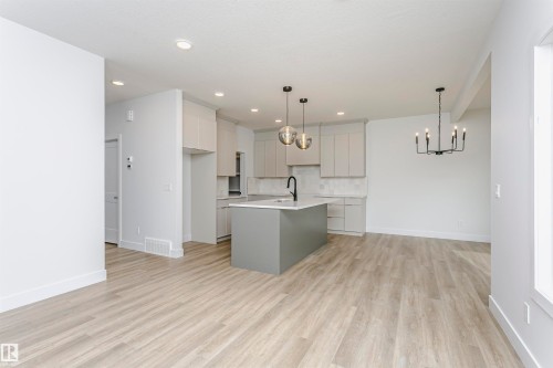 Contemporary kitchen featuring a center island with a black faucet, light gray cabinetry, and a subway tile backsplash - 6210 Dansereau Crescent, Beaumont, AB 