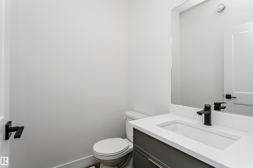 Bathroom vanity featuring a matte black faucet, undermount sink, and a light-toned countertop - 6210 Dansereau Crescent, Beaumont, AB 