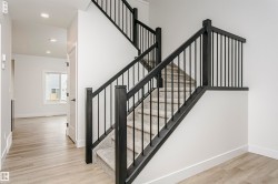 Staircase featuring dark wood-finish newel posts and railings with vertical metal balusters, carpeted treads, and risers - 