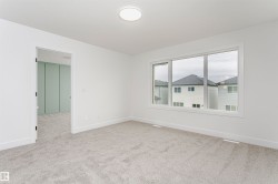 Bright interior space featuring a large three-panel window, light gray carpeting, and a flush-mount ceiling light fixture - 