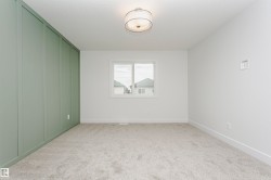 Room featuring a light green accent wall with vertical paneling, white walls, and light gray carpeted flooring - 