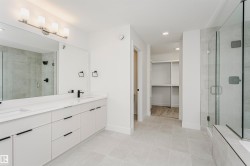 Spacious bathroom featuring a dual vanity with white cabinetry, quartz countertops, and matte black fixtures - 