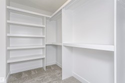 White custom closet system featuring multiple shelves, hanging rods, and gray carpet flooring - 
