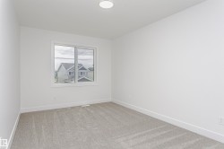 Bright room with soft gray carpeting, white walls, and a large window featuring white trim - 