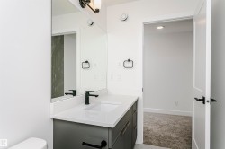 Bathroom vanity with a white countertop and dark gray cabinetry, featuring an undermount sink and a matte black single-handle faucet - 