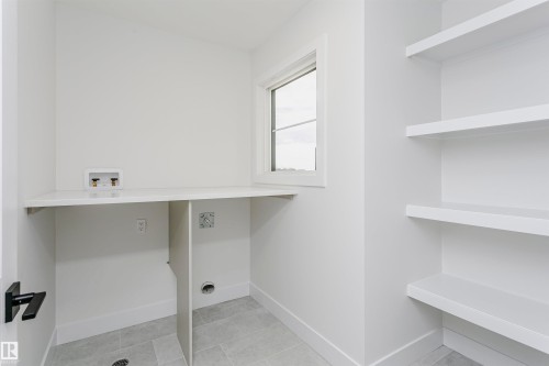 Dedicated laundry area featuring a white countertop, plumbing hookups, and a window for natural light - 6210 Dansereau Crescent, Beaumont, AB 