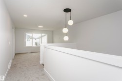 Bright upper landing featuring a contemporary three-globe pendant light, recessed lighting, white wall and trim finishes, gray carpet, and large windows - 