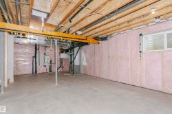Unfinished basement with concrete flooring, exposed wood joists, and insulated walls - 