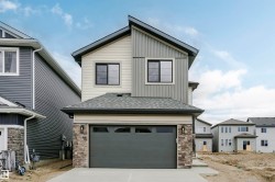 Modern two-story residence featuring a combination of light and dark siding, stone accents, and a dark shingle roof - 