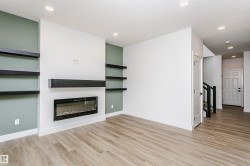 Modern living area featuring a built-in electric fireplace with a black mantel, recessed lighting, and wood-finish flooring - 