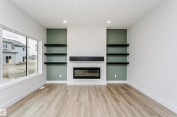 Open-concept living space featuring a contemporary electric fireplace with a dark wood mantel and accent wall - 