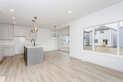 Open-concept kitchen and living area featuring wood-finish flooring, recessed lighting, and large windows - 
