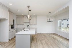 Open-concept living space featuring a kitchen island with sink, light wood-finish flooring, recessed lighting, and a multi-pane window - 