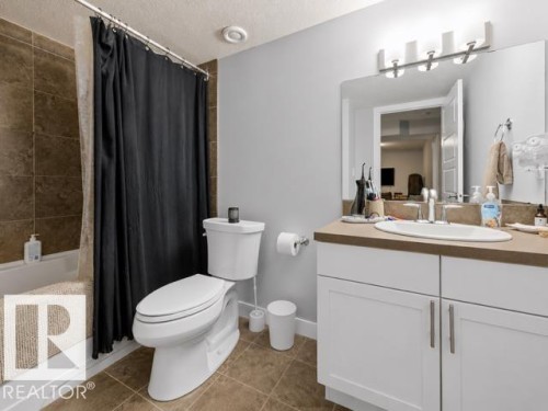 Bathroom featuring a white vanity with slab countertop, undermount sink, and brushed nickel fixtures - 607 40 Street, Edmonton, AB 