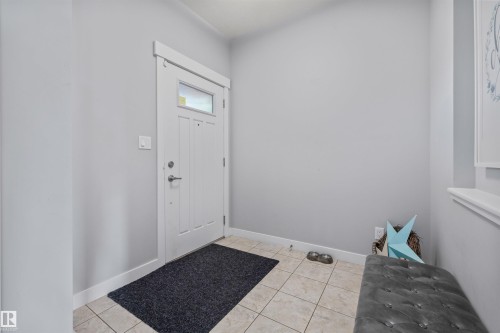 Entryway featuring a white paneled door with transom window, light-toned tile flooring, and neutral wall paint - 607 40 Street, Edmonton, AB 