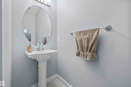 Pedestal sink with chrome fixtures and a round mirror - 607 40 Street, Edmonton, AB 
