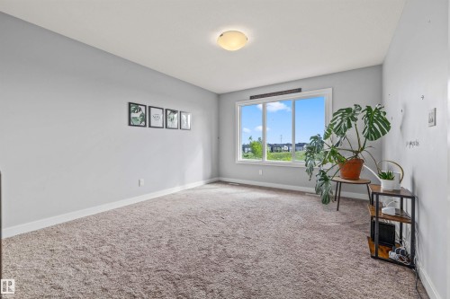 Carpeted room featuring light gray walls, a flush-mount ceiling light, and a large window with white trim - 607 40 Street, Edmonton, AB 