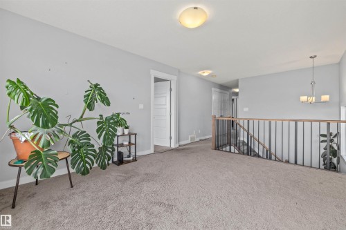 Carpeted upper-level landing featuring a wood and metal stair railing, interior doors, and overhead dome lighting - 607 40 Street, Edmonton, AB 