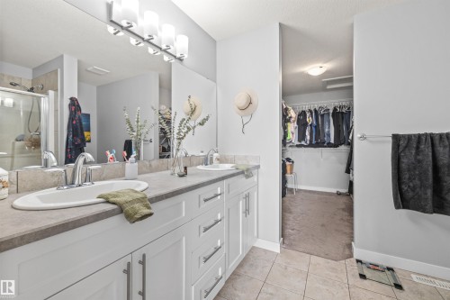 Dual vanity featuring white cabinetry with brushed nickel hardware, integrated sinks, and neutral countertops - 607 40 Street, Edmonton, AB 