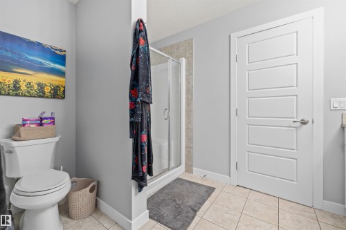 Bathroom featuring a glass-enclosed shower, neutral-toned tiled flooring, and a contemporary five-panel interior door - 607 40 Street, Edmonton, AB 