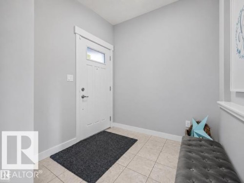 Entryway featuring a paneled door with frosted glass insert, white trim, and light-colored tile flooring - 607 40 Street, Edmonton, AB 