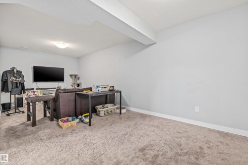 Spacious room featuring neutral wall paint, light brown carpet, and a white ceiling with a single flush-mount light fixture - 607 40 Street, Edmonton, AB 