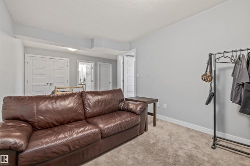 Carpeted area featuring light gray walls, white baseboards, and a textured ceiling - 607 40 Street, Edmonton, AB 