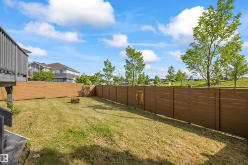Expansive backyard featuring a leveled lawn, complete wood privacy fencing, and an elevated wood deck - 607 40 Street, Edmonton, AB 