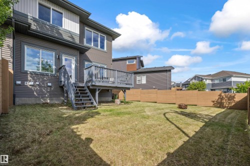 Rear exterior featuring a spacious yard, full-height privacy fencing, and a multi-level wooden deck with stairs to grade - 607 40 Street, Edmonton, AB 
