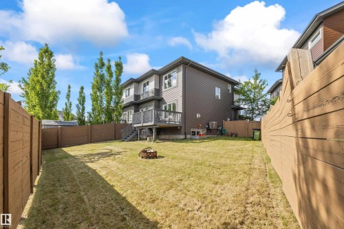 Expansive fenced backyard with a raised wooden deck, exterior stairs, and a multi-level siding facade - 607 40 Street, Edmonton, AB 