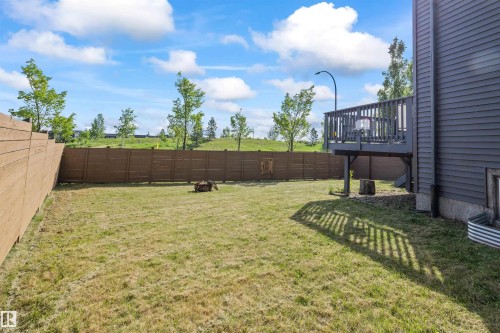 Spacious backyard featuring a wooden privacy fence, a raised deck with railings, and a window well on the side of the property - 607 40 Street, Edmonton, AB 