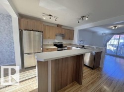Kitchen featuring wood-finish cabinetry, stainless steel appliances, light-toned countertops, a breakfast bar, and wood-finish flooring - 