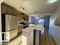 Kitchen featuring stainless steel appliances, wood-finish cabinetry, light-toned countertops, and wood-finish flooring - 