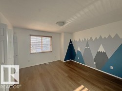 Interior room featuring wood-finish flooring, a white ceiling with a flush-mount light fixture, and a window with horizontal blinds - 