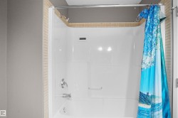 The bathroom features a pristine white shower and tub unit, complete with a shower head and faucet - 