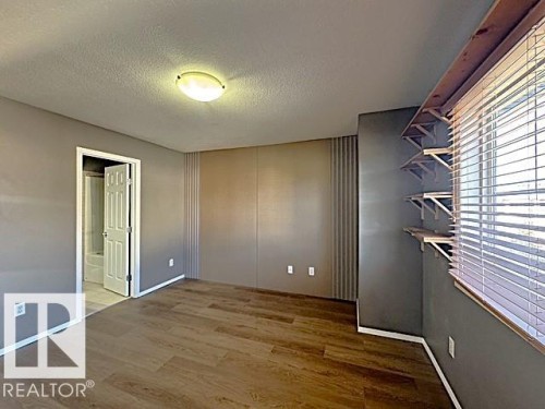 Interior space featuring wood-finish flooring and a flat-panel ceiling light fixture - #13 3751 12 Street, Edmonton, AB 