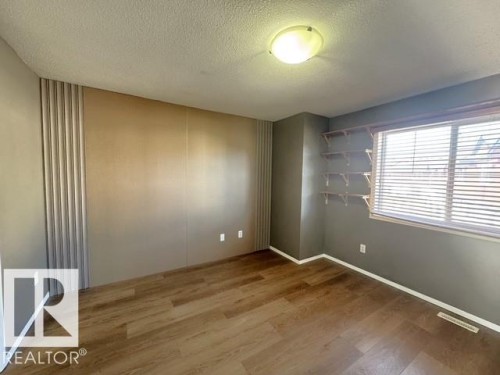 Room featuring wood-finish flooring and a textured ceiling - #13 3751 12 Street, Edmonton, AB 