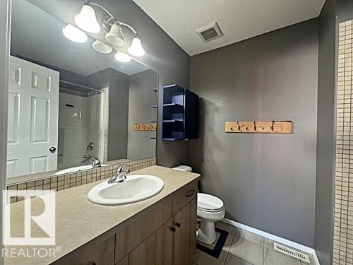 Bathroom vanity featuring an integrated sink, laminate countertop, and wood-finish cabinetry - #13 3751 12 Street, Edmonton, AB 