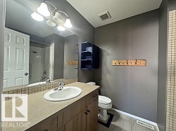 Bathroom vanity featuring an integrated sink, laminate countertop, and wood-finish cabinetry - 